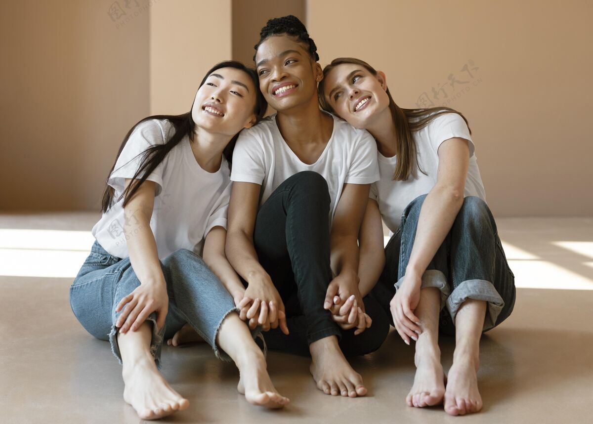 年轻满脸笑容的女人坐在地板上中镜头女人友谊