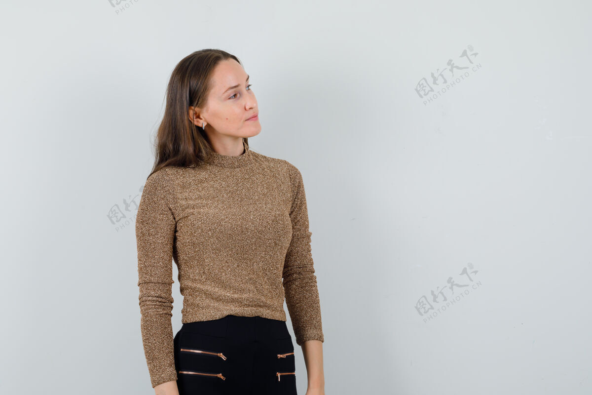 肖像年轻的女性穿着金色的衬衫 看着一边 看上去很平静 前面的视野文本空间人脸冷静