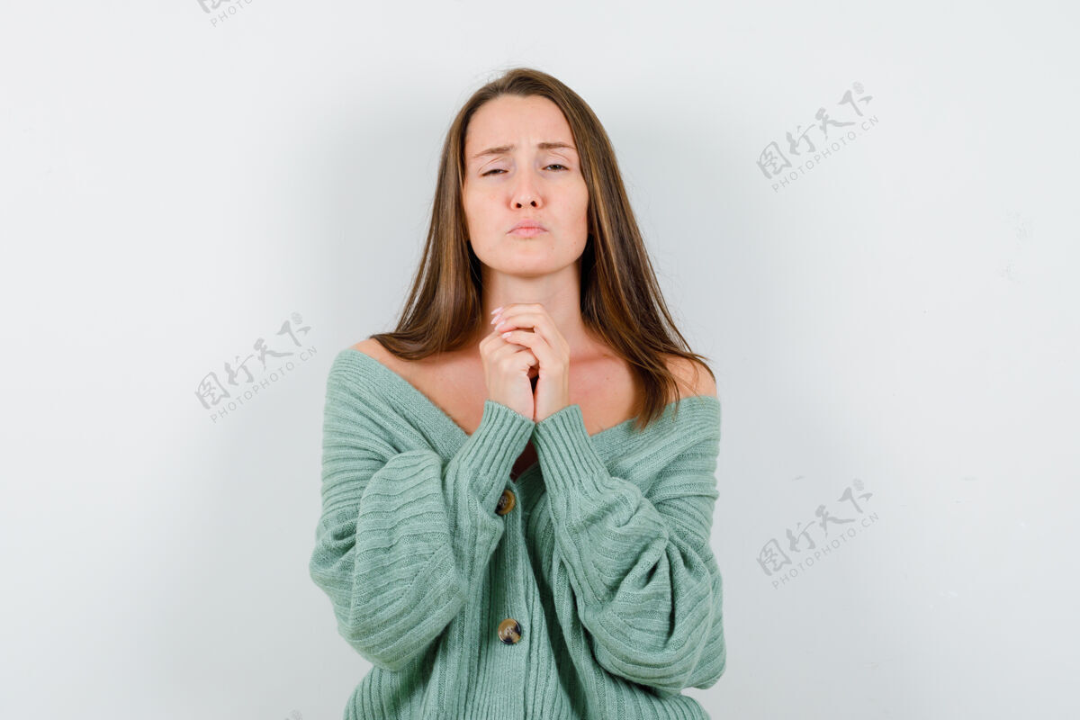 前面身穿针织衫的年轻女孩双手紧握祈祷姿势 目光集中正面视图美容针织乐趣