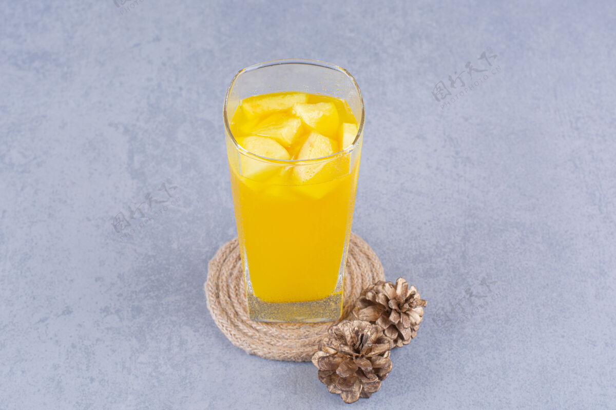 玻璃松果 一杯果汁和三脚架 放在大理石上可口松果美味