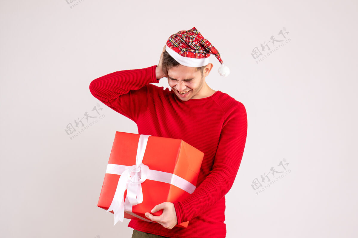 头前视图：戴着圣诞帽的年轻人把头举在白色背景上礼物微笑举行