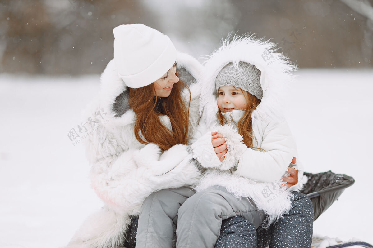 寒冷一家人在一起过圣诞节一个公园里的女人和小女孩带着雪橇的人婴儿幼儿毛衣