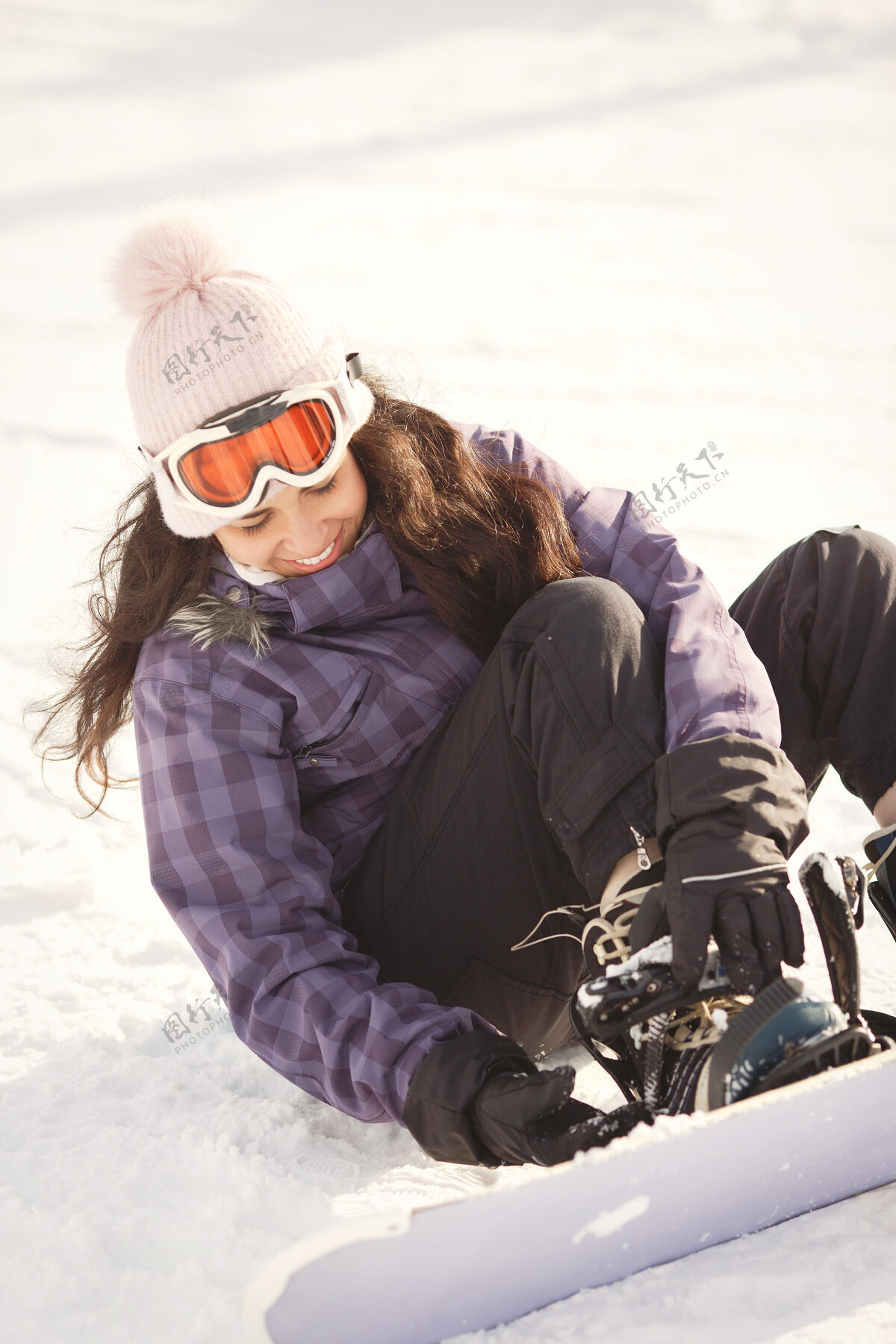 乐趣试图爬上滑雪板的女孩坐在雪地上的女人紫色套装寒冷微笑白色