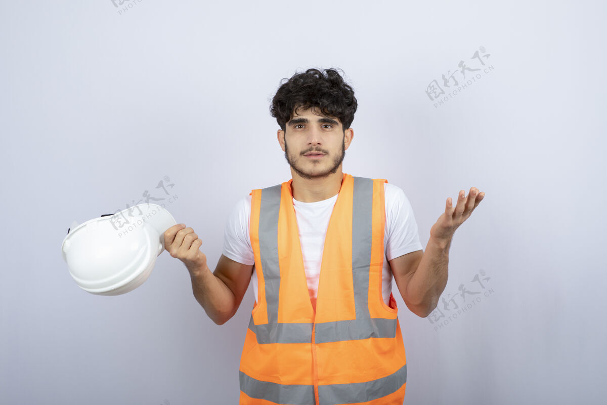 工作穿着制服的帅哥站在白色的墙上高质量的照片工作安全帽年轻人
