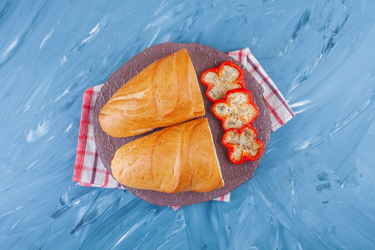 风味把辣椒片和面包放在茶巾的木板上 放在蓝色的桌子上酵母烘焙美味