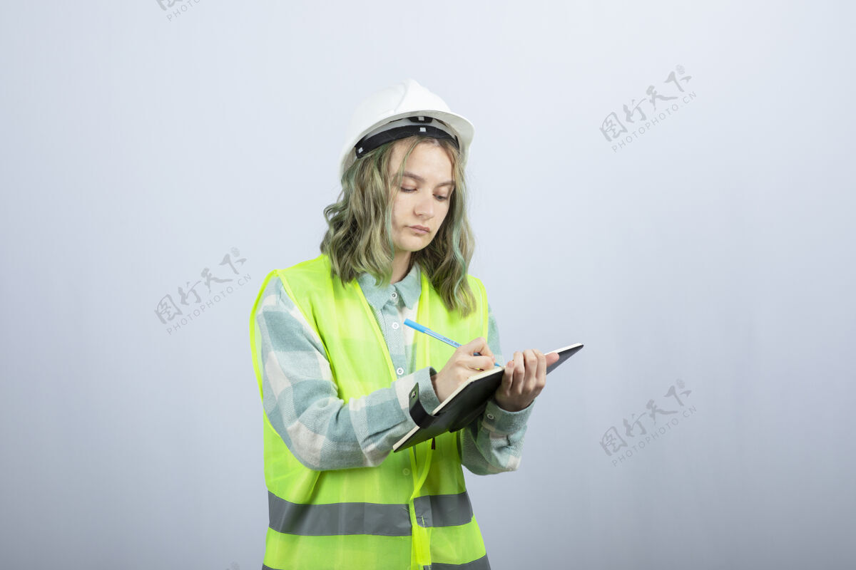 写作年轻的女工程师在白墙上的笔记本上写下她的想法高质量的照片穿年轻人工程师