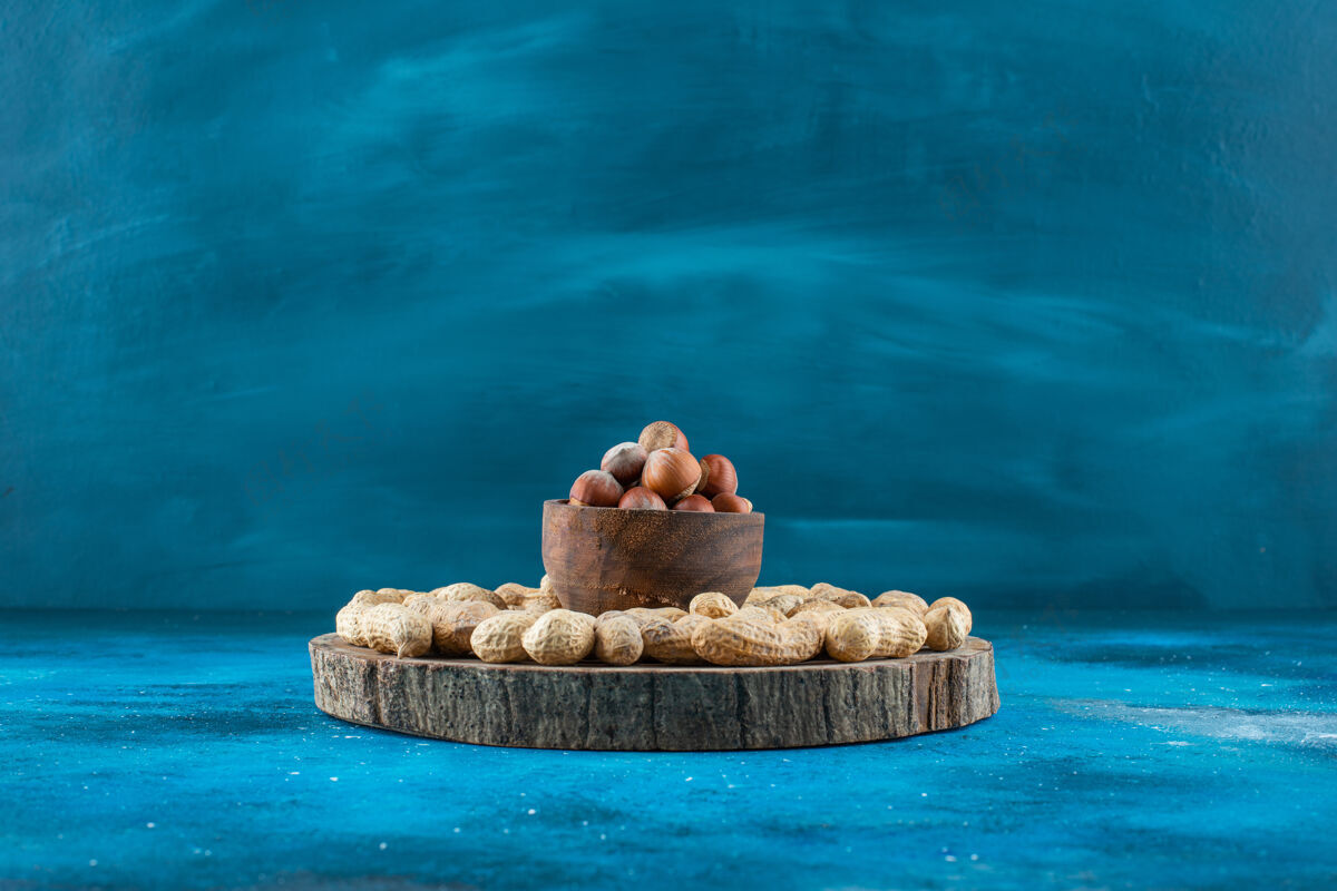 蛋白质把榛子放在碗里 在蓝色的表面放上花生碗美味坚果