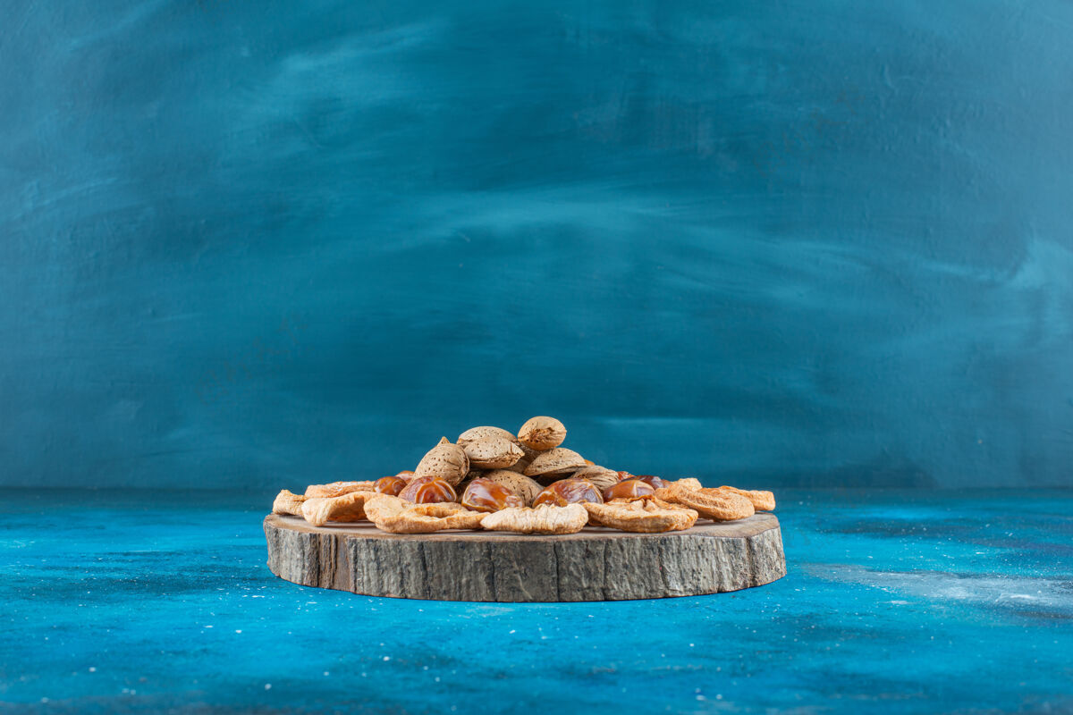 美味把坚果和干果放在蓝色的木板上壳板坚果