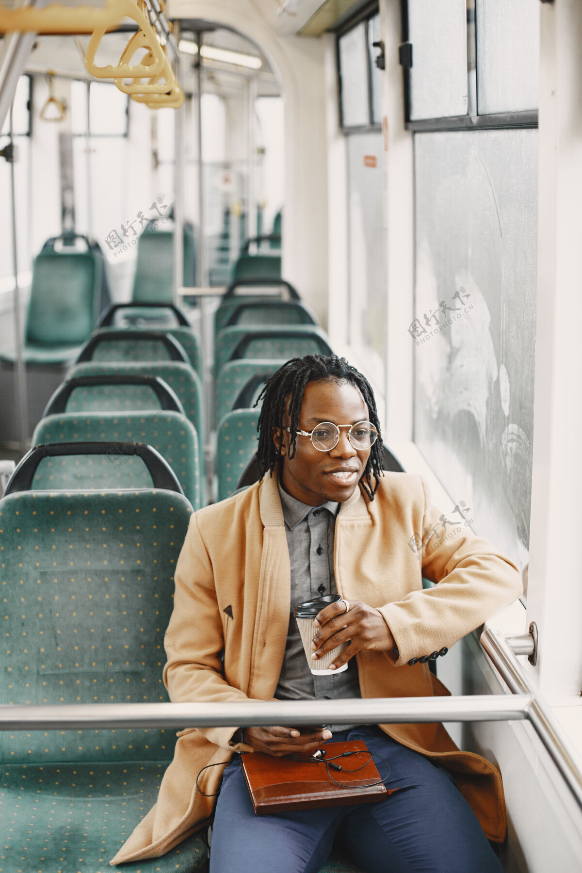 城市一个非洲裔美国人坐在城市巴士上一个穿棕色外套的人一个喝咖啡的人美国人通勤黑人