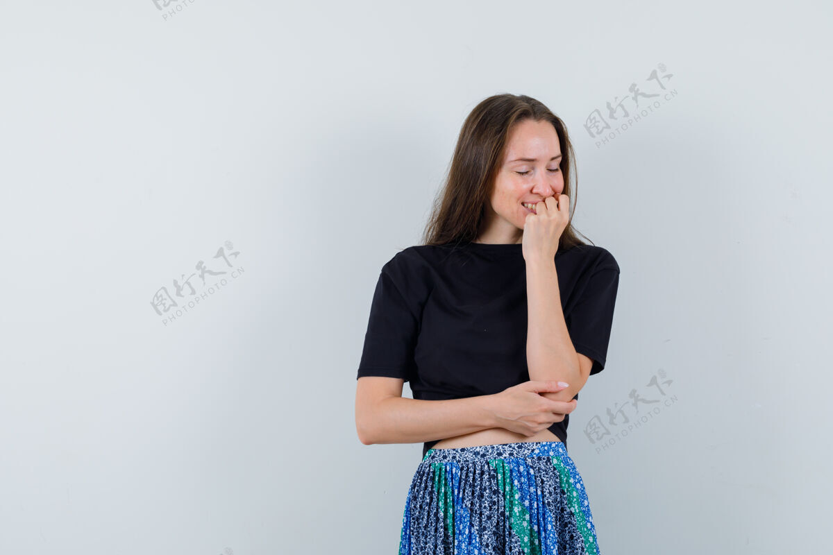 头发一位年轻女子 手托下巴 身穿黑色t恤和蓝色裙子 在镜头前摆出迷人的姿势亚洲人干净女性