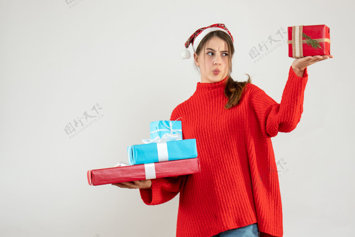 礼物前视图困惑的女孩与圣诞帽比较她的圣诞礼物圣诞老人空间比较