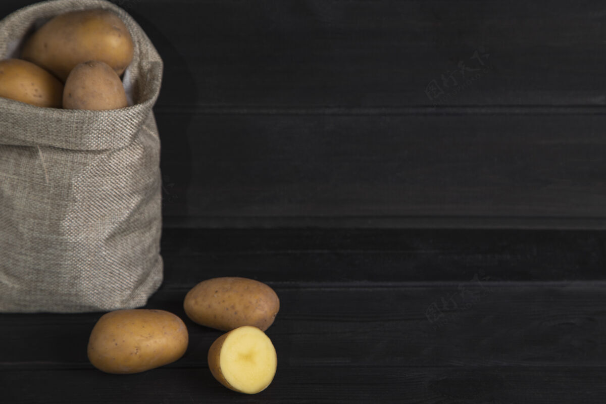 健康一堆新鲜的生土豆 用旧麻布包在黑色的表面上高质量的照片农场营养生的