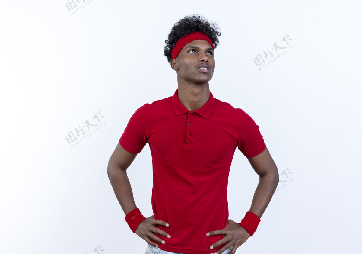 非裔美国人看着一边思考的年轻黑人美国运动男子戴着头带和腕带把双手放在臀部隔离在白色背景穿壁板臀部