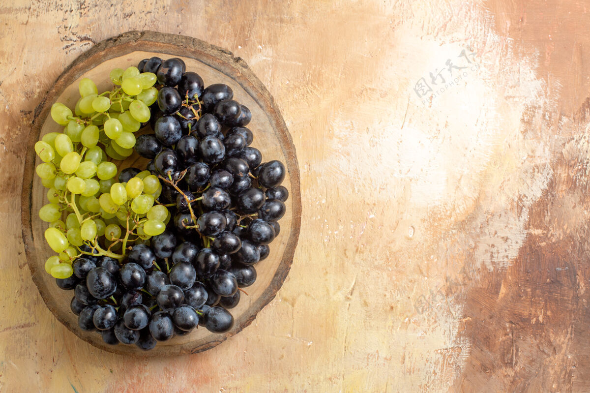 浆果顶视图葡萄绿色和黑色的葡萄串在木制砧板上收获有机葡萄酒