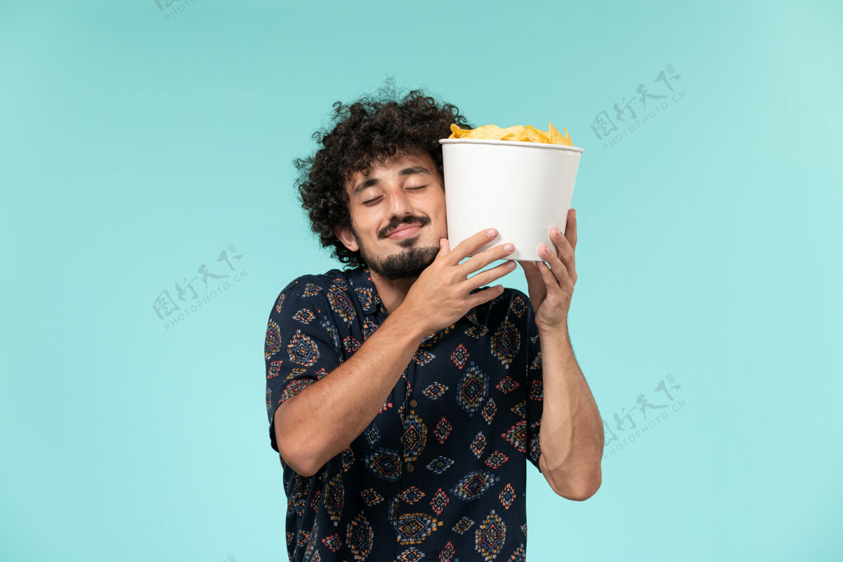 肖像前视图年轻人拿着土豆cips放在蓝色书桌上电影院电影院男电影视图土豆