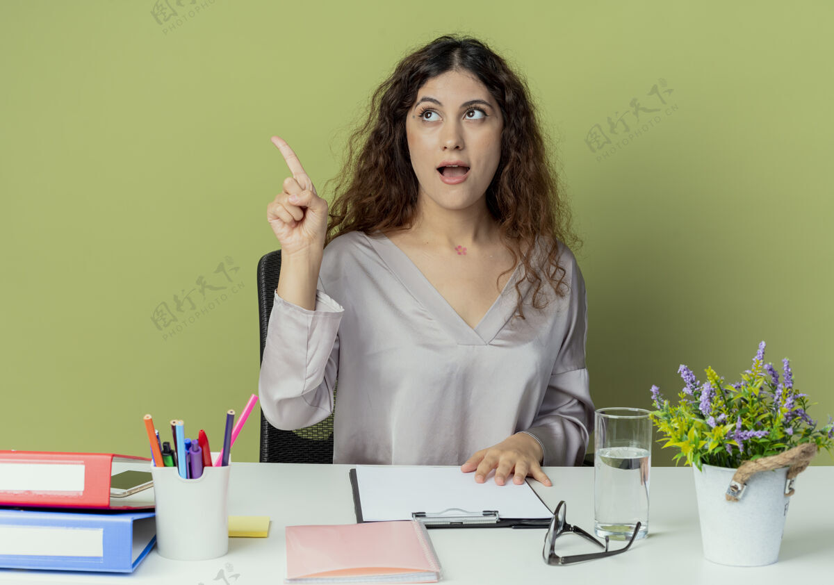 点看着侧思考年轻漂亮的女办公室工作人员坐在办公桌旁 办公工具点在一边孤立的橄榄背景与复印空间办公室工具办公桌