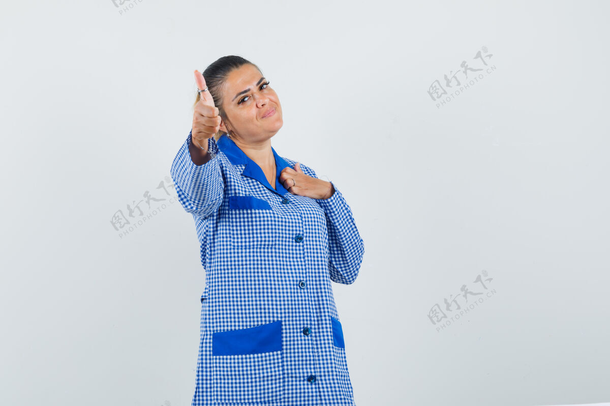 女孩年轻女子指着胸前 手拿蓝色方格布睡衣衬衫 看起来很漂亮 正面图漂亮手指