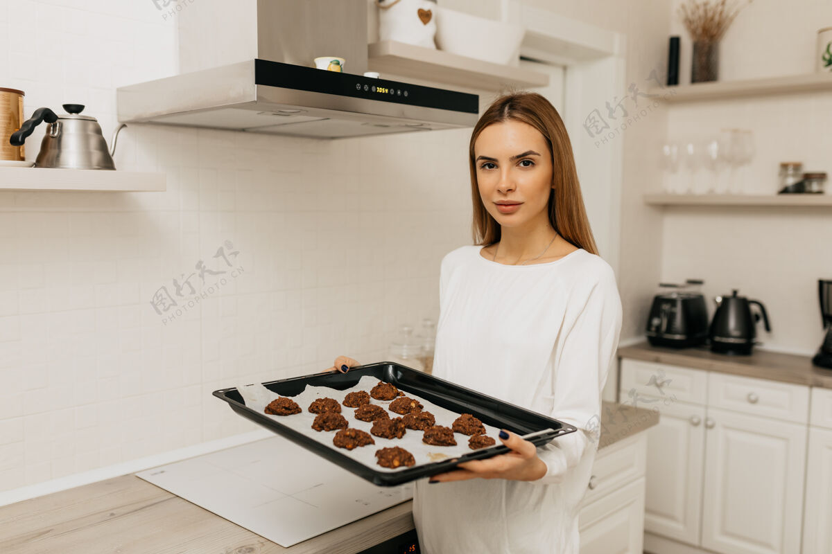 金发一位穿着白衬衫 浅棕色头发的年轻女士正在厨房里做自制的巧克力饼干阅读爱好体重