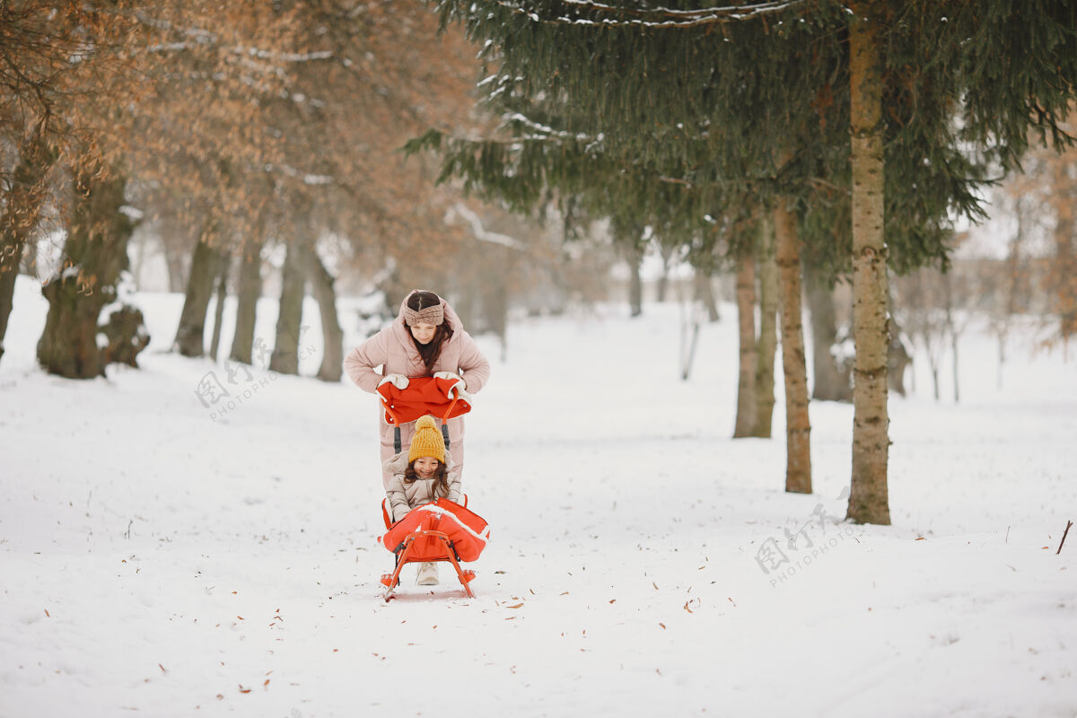 小带着雪橇的公园里的女人和小女孩雪自然幼儿