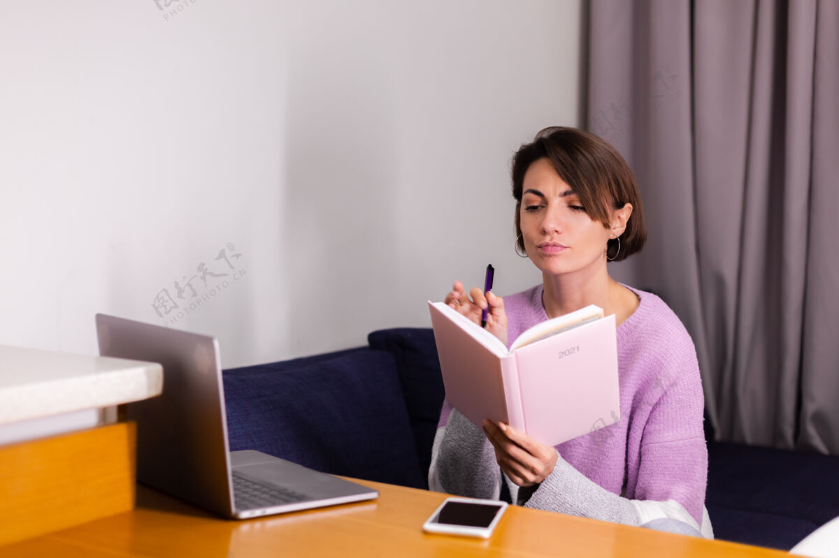 年轻女人在家拿着记事本想着计划思考日记电脑