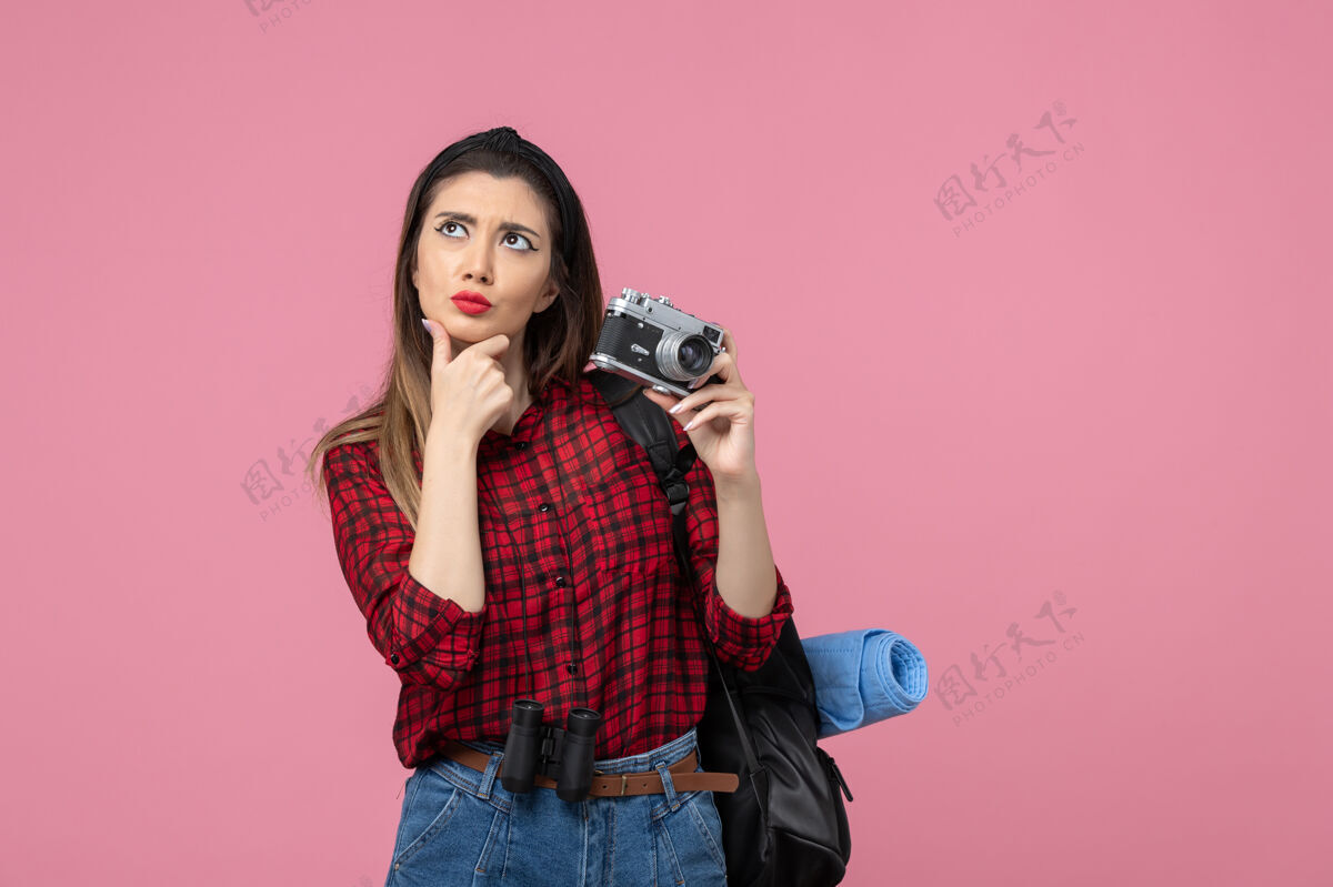 年轻女性前视图年轻女性正在用相机拍摄浅粉色背景的女性照片拍摄黑发电话