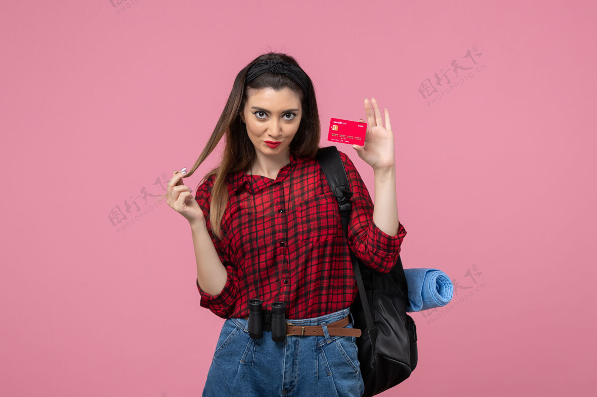 成人正面图身穿红色衬衫的年轻女性 浅粉色背景上有银行卡 女性颜色为人类人脸头发