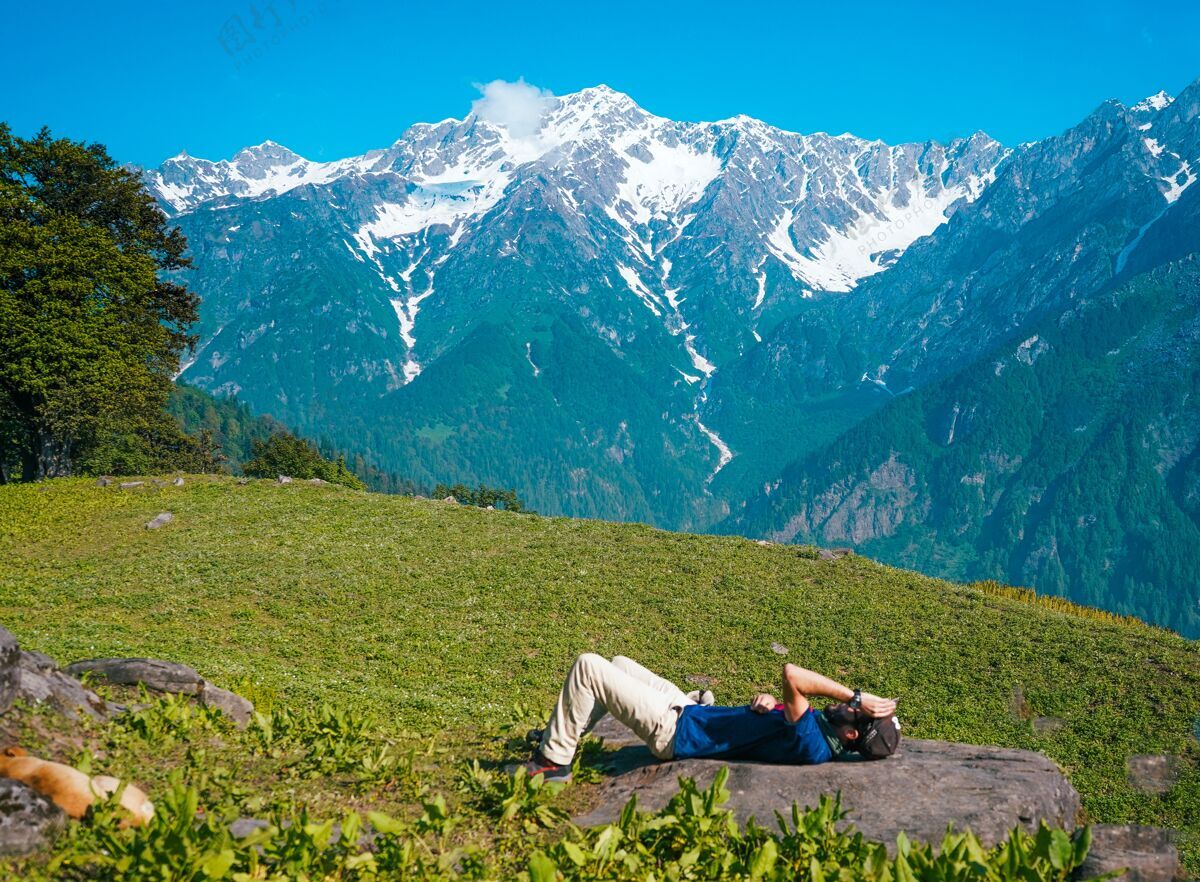日光浴孤独的男人躺在山上的草地上晒太阳风景田野躺着