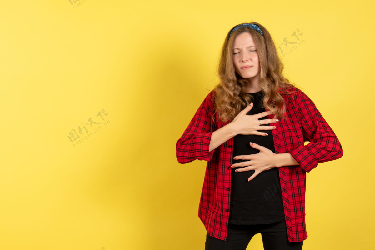 情感正面图穿着红色格子衬衫的年轻女性在浅黄色背景上摆姿势模特女孩女人颜色情感人类姿势人女孩
