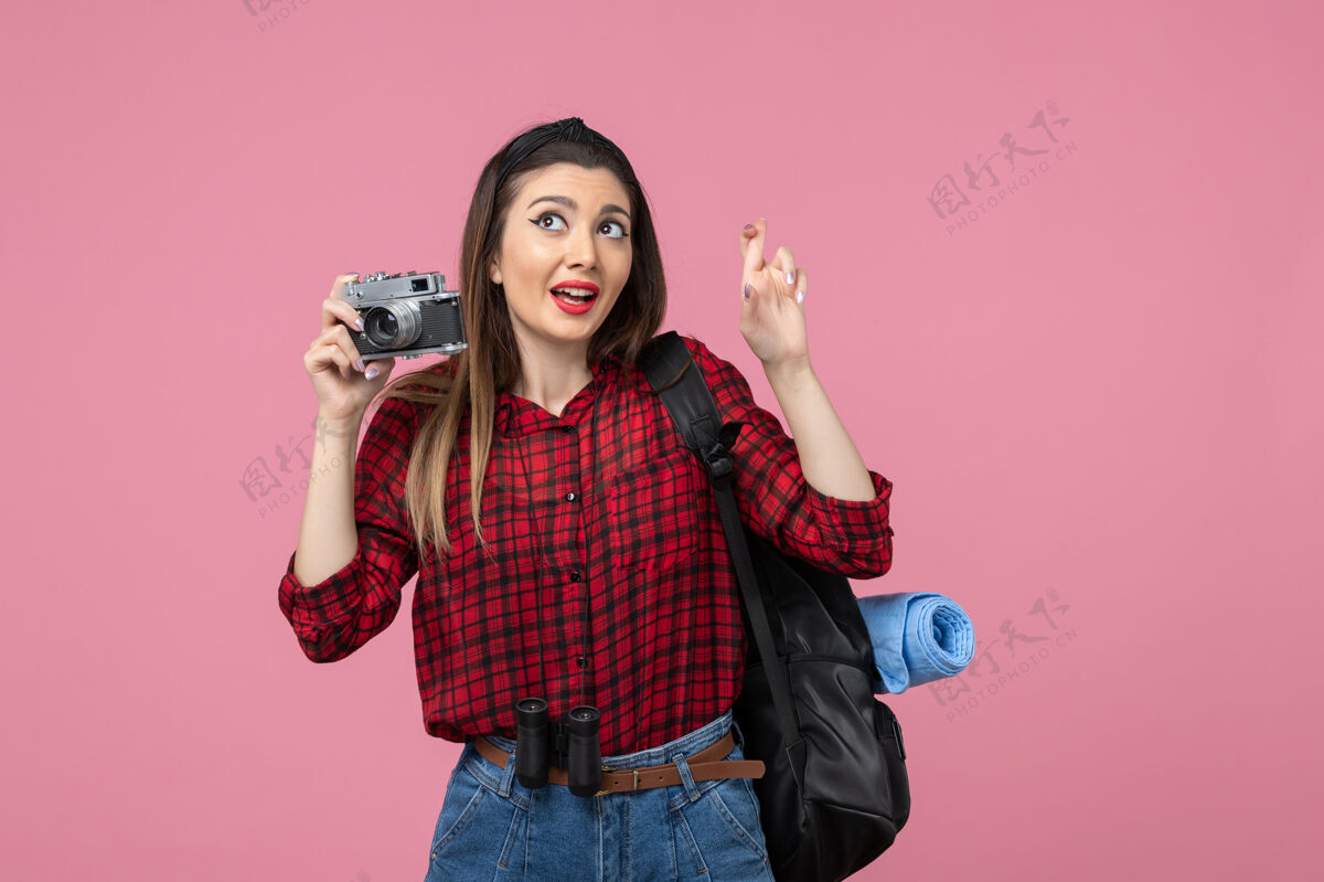 女士前视图年轻女性用相机在粉红色背景上拍照女性颜色年轻女性人物相机