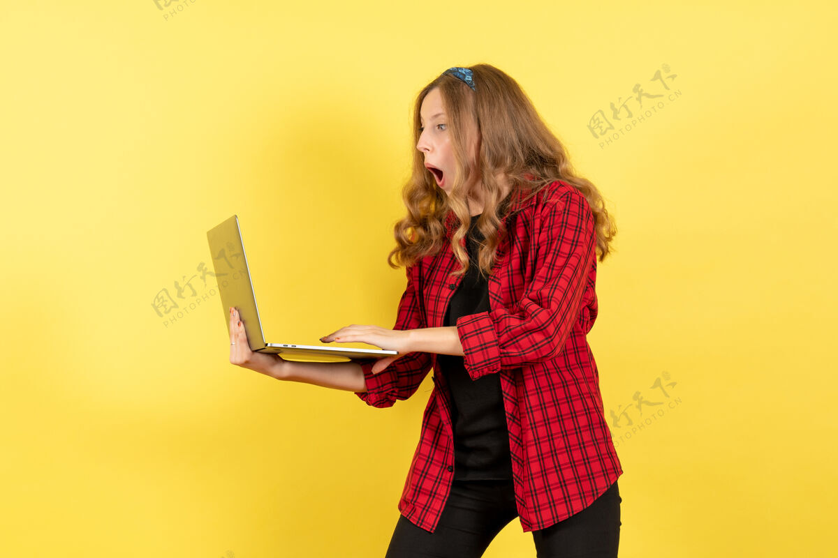人前视图穿着红色格子衬衫的年轻女性用她的笔记本电脑在黄色背景上展示女性人类情感模型时尚女孩成人人格子