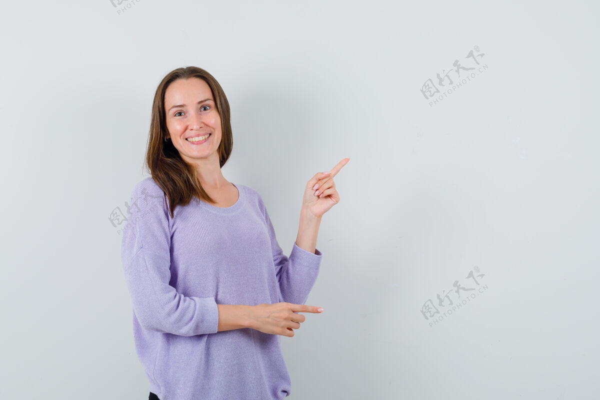 健康年轻的女性指着旁边的淡紫色衬衫 看起来积极旁白魅力化妆