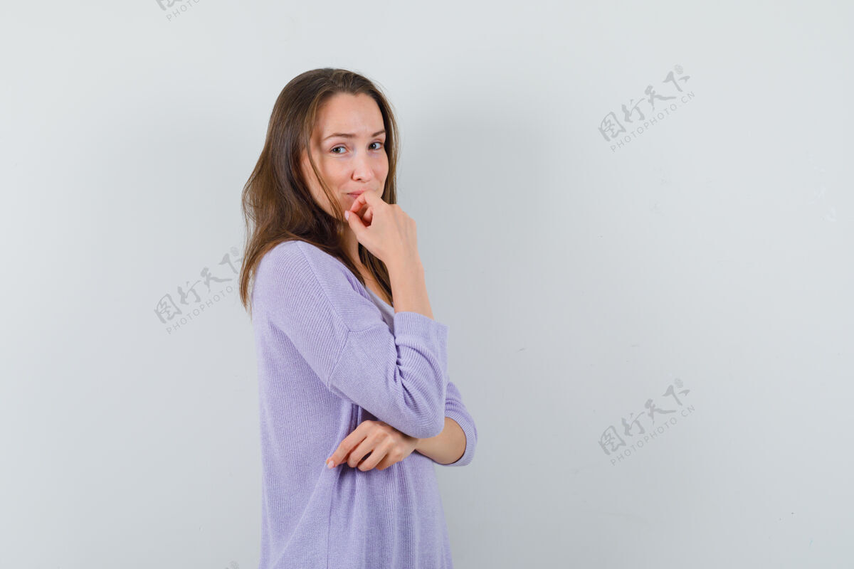 漂亮穿着淡紫色上衣的年轻女性一边摆姿势 一边看着一边 看起来很可爱衬衫手一旁