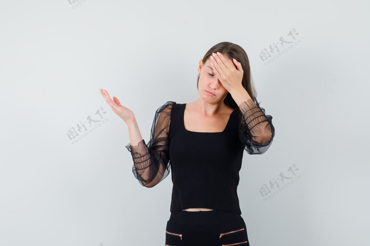 姿势一个年轻的女人手放在头上 一边展示左边的东西 穿着黑色上衣 看起来很紧张手衬衫漂亮