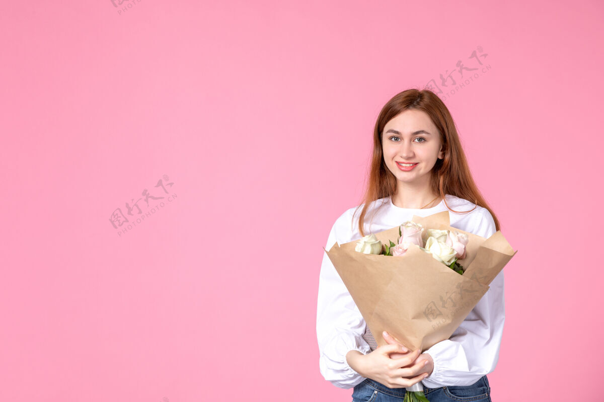 年轻的女性正面图：年轻女性 带花朵 在粉色背景上呈现女性节水平女性三月女性约会平等玫瑰性感花束花人