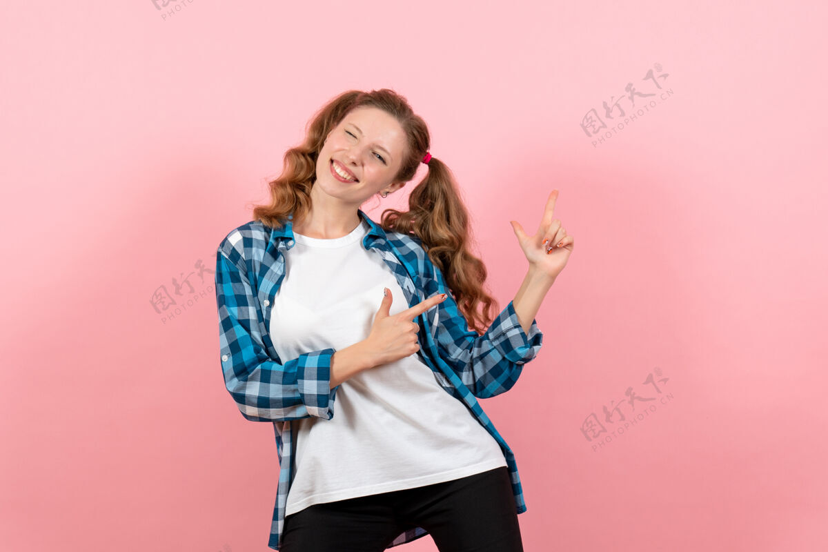 格子正面图身着格子衬衫的年轻女性在粉色背景上微笑造型年轻女性情感童装孩子成人漂亮