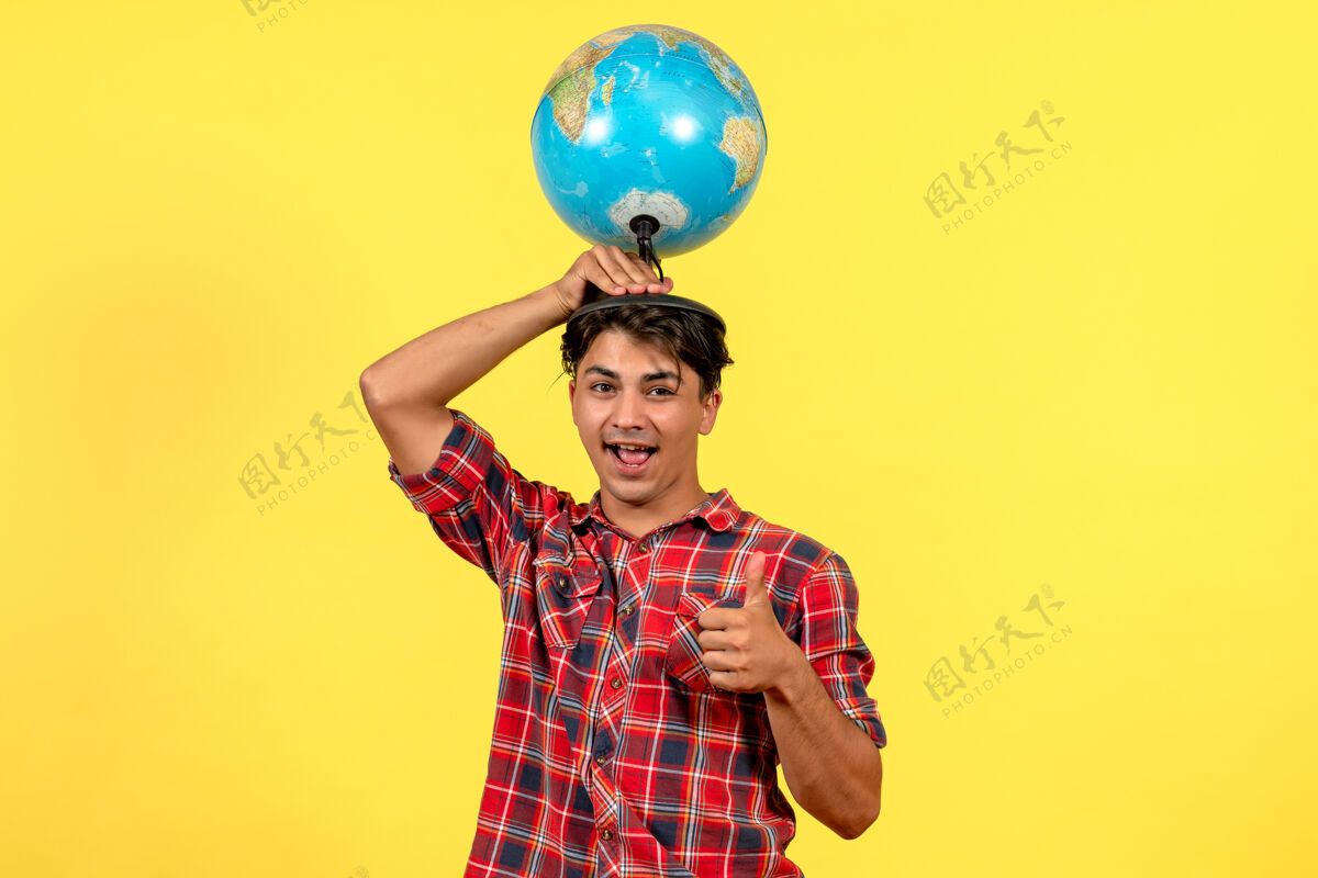 乐趣正面图年轻男性手持地球仪 背景为黄色男性模特色气球地球男性