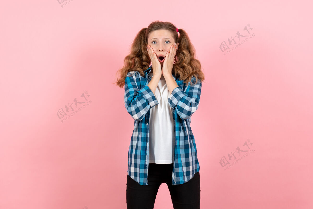 肖像正面图身着蓝色格子衬衫的年轻女性在粉色书桌上摆姿势儿童青春情感模特时尚女人色衬衫成人格子