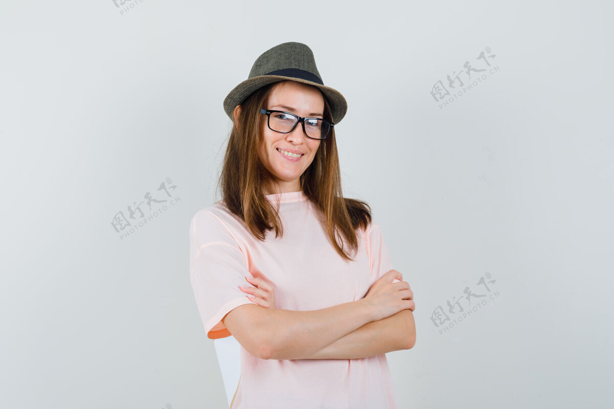 孩子年轻的女孩交叉双臂站在粉红色的t恤帽子 看起来很自信可爱帽子童年