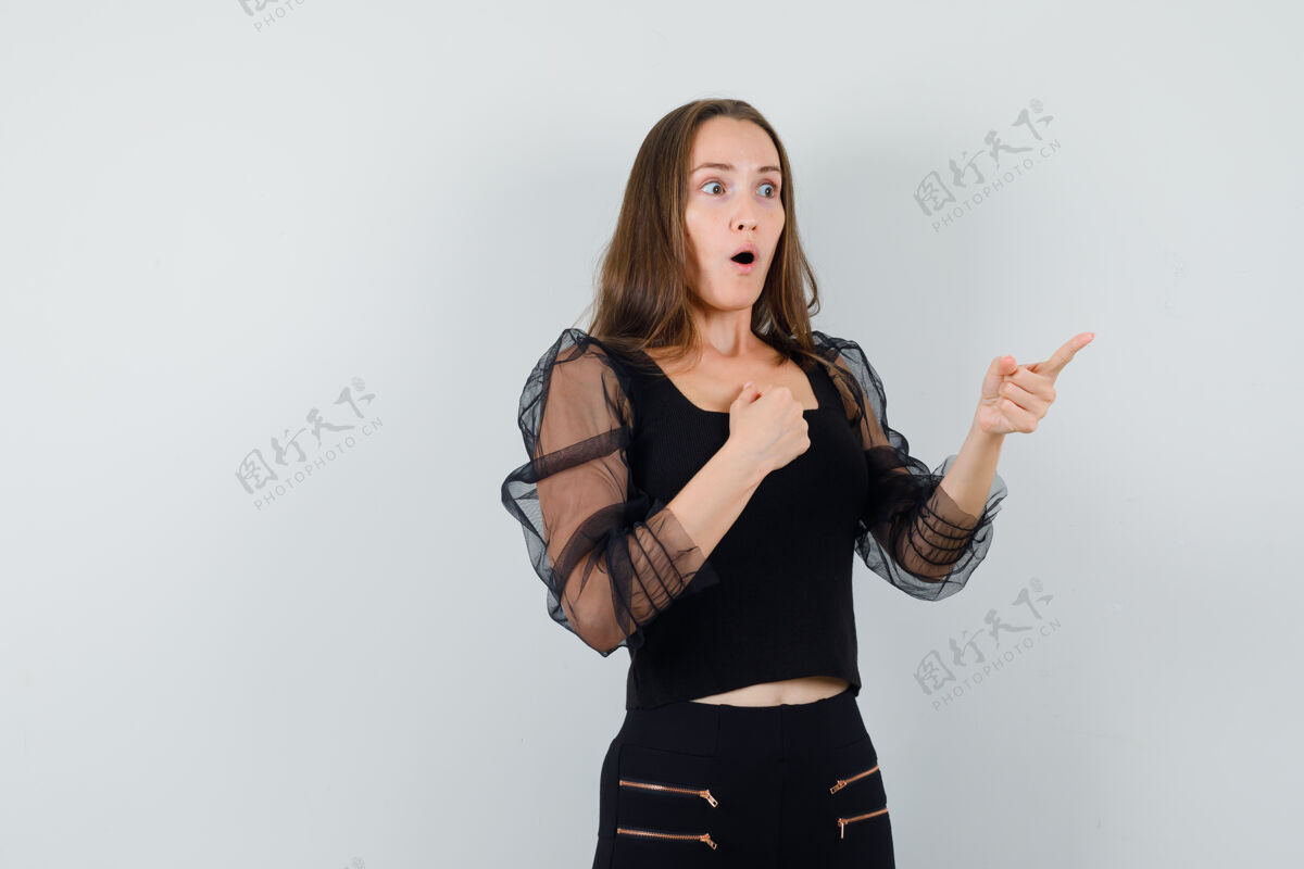 指向一个穿着黑色上衣的漂亮女人把拳头放在胸前 一边指着一边 看上去很惊讶头发女士而