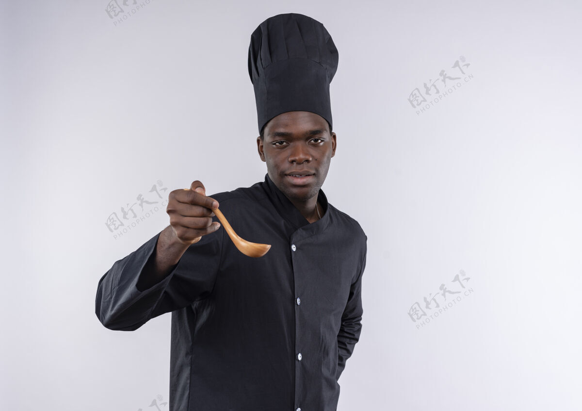 制服身着厨师制服的年轻自信的美国黑人厨师拿着木勺 看着白色的相机 留着复印空间木头非裔美国人空间
