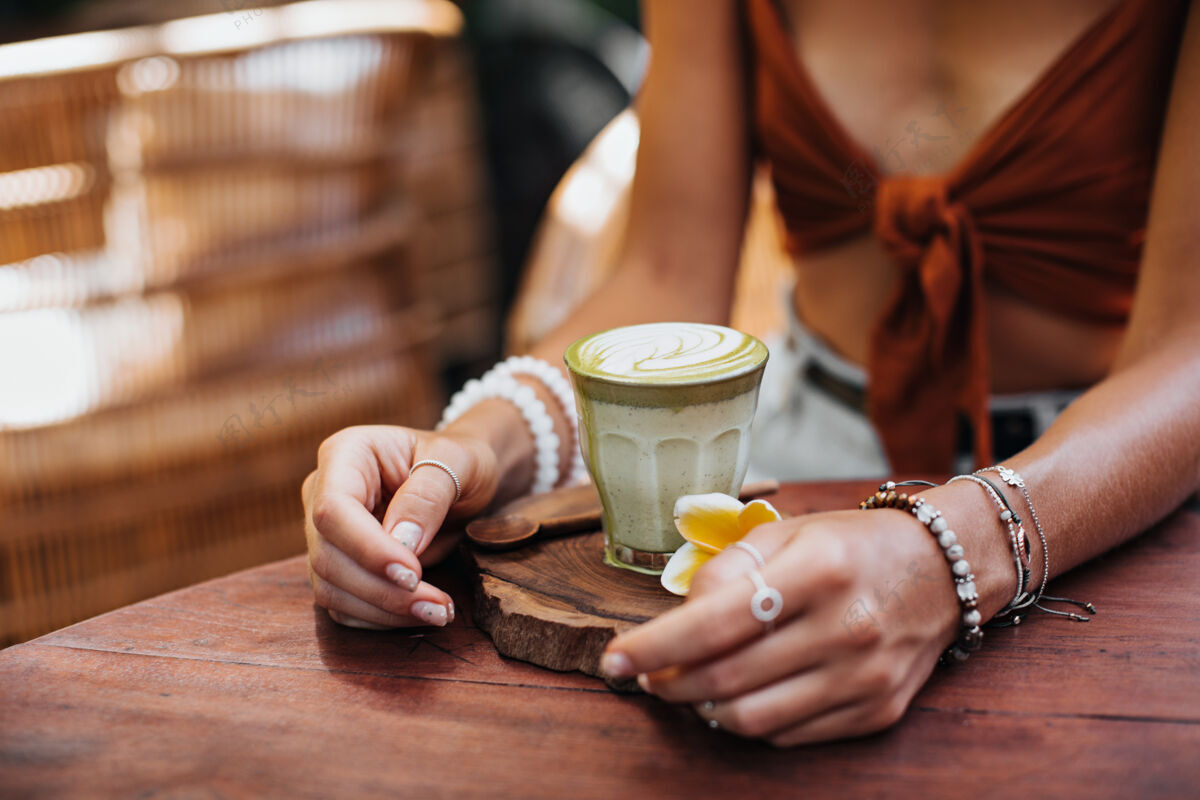 杯子穿着棕色胸罩的女人坐在咖啡馆里 手里拿着一杯抹茶拿铁杯子抹茶新鲜