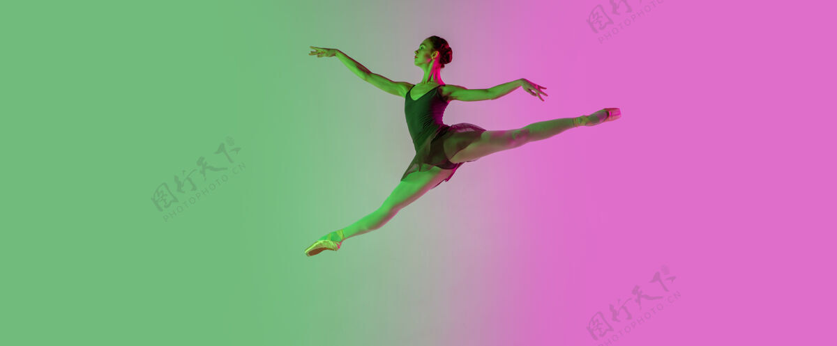 舞蹈轻年轻而优雅的芭蕾舞演员在霓虹灯下被隔离在渐变的粉绿色墙壁上艺术 动作 动作 灵活性 灵感概念灵活的芭蕾舞演员 失重跳跃渐变动作情感