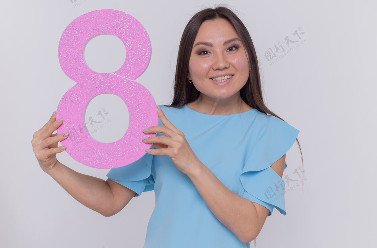 庆祝快乐而积极的亚洲女人拿着纸板做的8号 站在白色的墙上 面带微笑 兴高采烈地庆祝国际妇女节微笑举行快乐