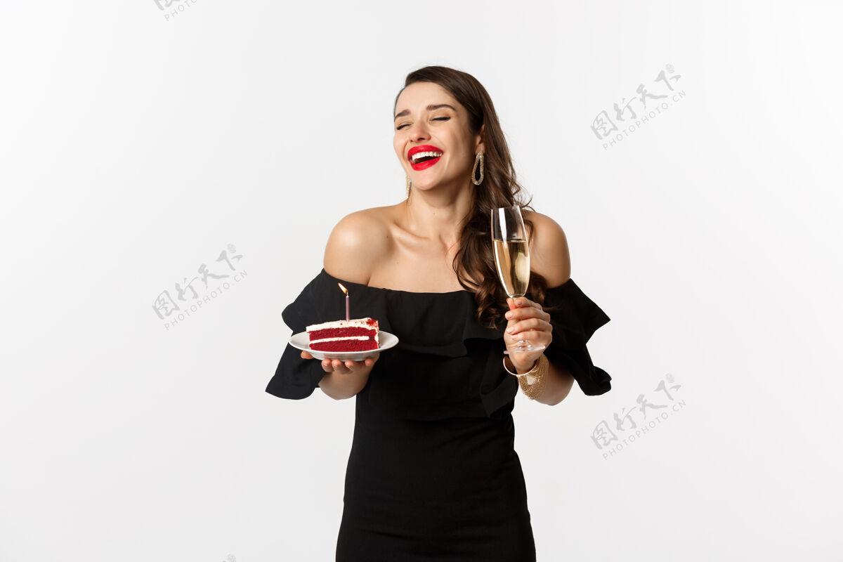 时尚庆祝和派对概念时尚女人拿着生日蛋糕和蜡烛 喝着香槟 开心地笑着 站在白色背景下表情女性衣服