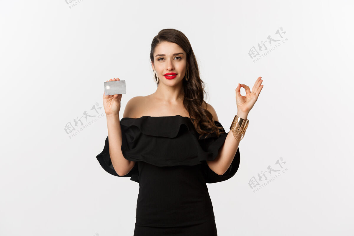 唇膏美丽和购物理念穿着奢华珠宝和黑色连衣裙的漂亮女人 展示OK标志和信用卡 站在白色背景上女人美丽表情