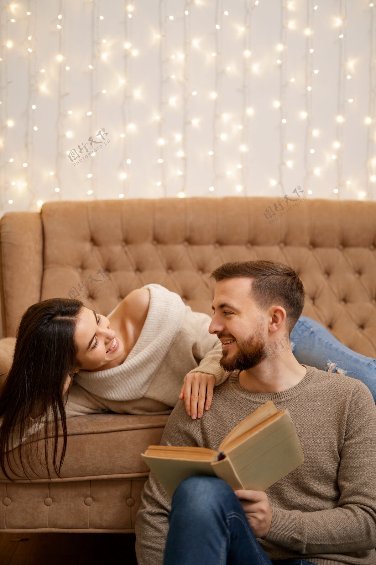 阅读年轻漂亮的情侣 彼此依偎在一起 面带微笑 女人捧着一本书沙发舒适休闲