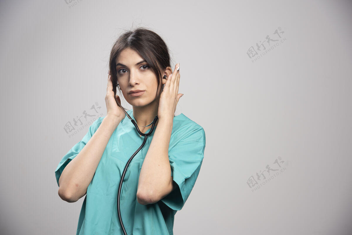医疗女医生拿着听诊器站在灰色的地板上听诊器个人工作