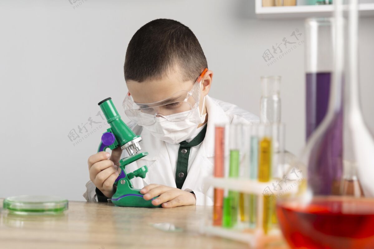 显微镜实验室里拿显微镜的男孩防护眼镜科学试管