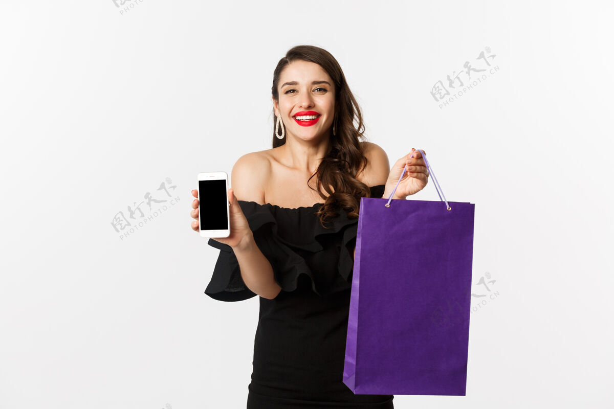 魅力美丽和购物概念美丽和时尚的女人展示手机屏幕和包 网上购物 站在白色背景下服装长发美丽