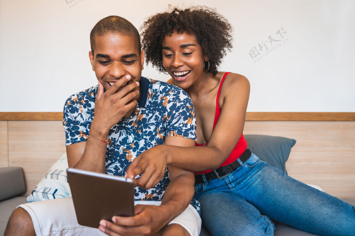 个人电脑拉丁年轻夫妇在家里放松和使用数字平板电脑的肖像科技和生活方式的概念平板电脑快乐女人